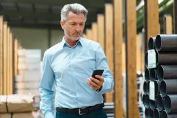 a person on a construction site looking at their phone, a bubble with an icon of heating floating away from their phone
